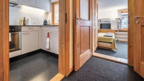 A compact kitchen with modern appliances, a small dining area with a bed, and a view of a snowy landscape. - Chalet Höckli 2 Appartement/Fewo,   4-Bettwohnung by Interhome (Arosa)