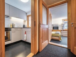 Eine kompakte Küche mit modernen Geräten, ein kleiner Essbereich mit einem Bett und Blick auf eine verschneite Landschaft.