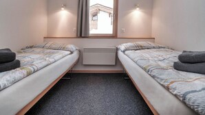 A twin room with two beds, a window with curtains, a radiator, and a view of a building outside. - Chalet Höckli 2 Appartement/Fewo,   4-Bettwohnung by Interhome (Arosa)