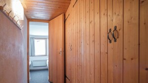 A narrow hallway with wooden walls and a carpeted floor leading to a room with a window. - Chalet Höckli 2 Appartement/Fewo,   4-Bettwohnung by Interhome (Arosa)