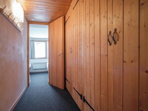 Ein schmaler Korridor mit Holzwänden und Teppichboden, der zu einem Zimmer mit einem Fenster führt.