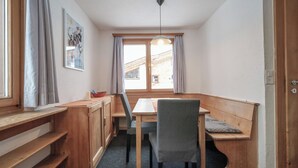 A compact dining area with a wooden table and chairs, a bench, and a window with curtains. - Chalet Höckli 2 Appartement/Fewo,   4-Bettwohnung by Interhome (Arosa)