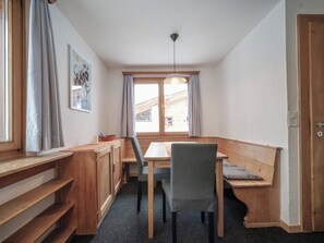 Ein gemütlicher Essbereich mit Holztisch und Stühlen, einer Bank und einem Fenster mit Vorhängen.