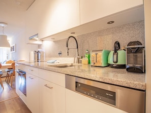 A modern kitchen with a stainless steel dishwasher, a granite countertop, and a coffee maker. - Rothornblick 57 by Arosa Holiday Appartement/Fewo, Bad, WC, 2-Bettwohnung by Interhome (Arosa)