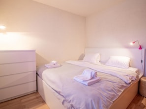 A bedroom with a bed, a nightstand, a lamp, and a dresser. - Rothornblick 57 by Arosa Holiday Appartement/Fewo, Bad, WC, 2-Bettwohnung by Interhome (Arosa)