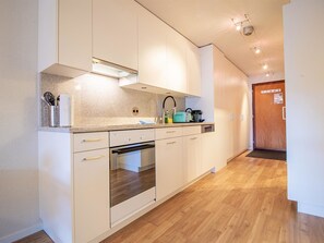 A modern kitchen with white cabinets, a built-in oven, and a countertop with various appliances. - Rothornblick 57 by Arosa Holiday Appartement/Fewo, Bad, WC, 2-Bettwohnung by Interhome (Arosa)