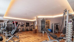 A gym with various exercise equipment, a wooden floor, and a wall-mounted television. - Rothornblick 57 by Arosa Holiday Appartement/Fewo, Bad, WC, 2-Bettwohnung by Interhome (Arosa)