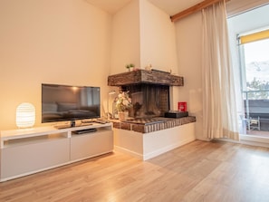 A modern living room with a flat-screen TV, a fireplace, and a large window. - Rothornblick 57 by Arosa Holiday Appartement/Fewo, Bad, WC, 2-Bettwohnung by Interhome (Arosa)