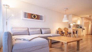 A modern living room with a sofa, a wooden coffee table, and a dining area with chairs and a table. - Rothornblick 57 by Arosa Holiday Appartement/Fewo, Bad, WC, 2-Bettwohnung by Interhome (Arosa)
