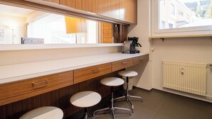 Een moderne keuken met houten kastjes, een aanrecht, een koffieapparaat en een raam met uitzicht op gebouwen.