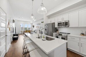 Una cocina moderna con armarios blancos, electrodomésticos de acero inoxidable y una isla central.