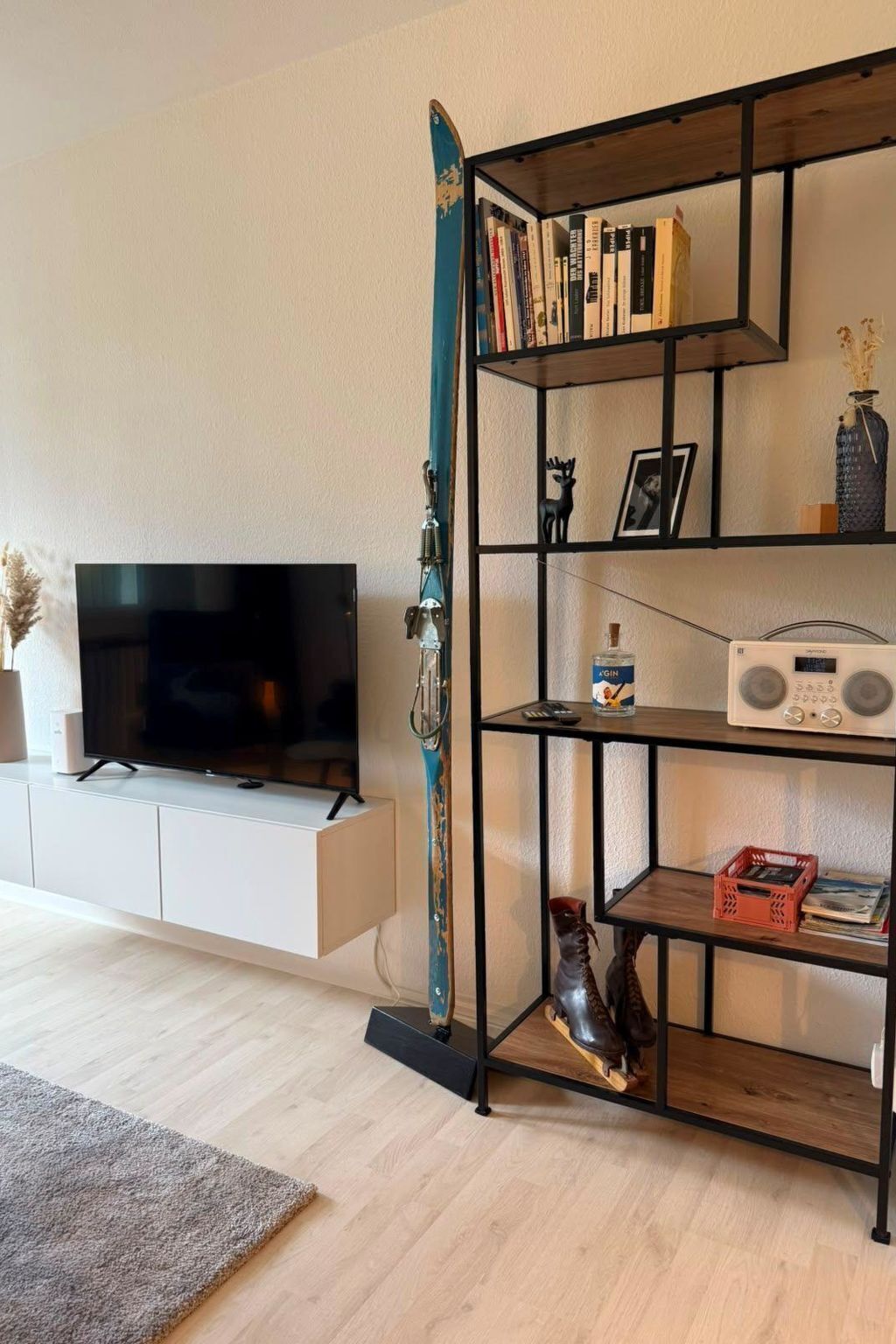 Ein Wohnzimmer mit Fernseher, Bücherregal und einem Ski an der Wand.