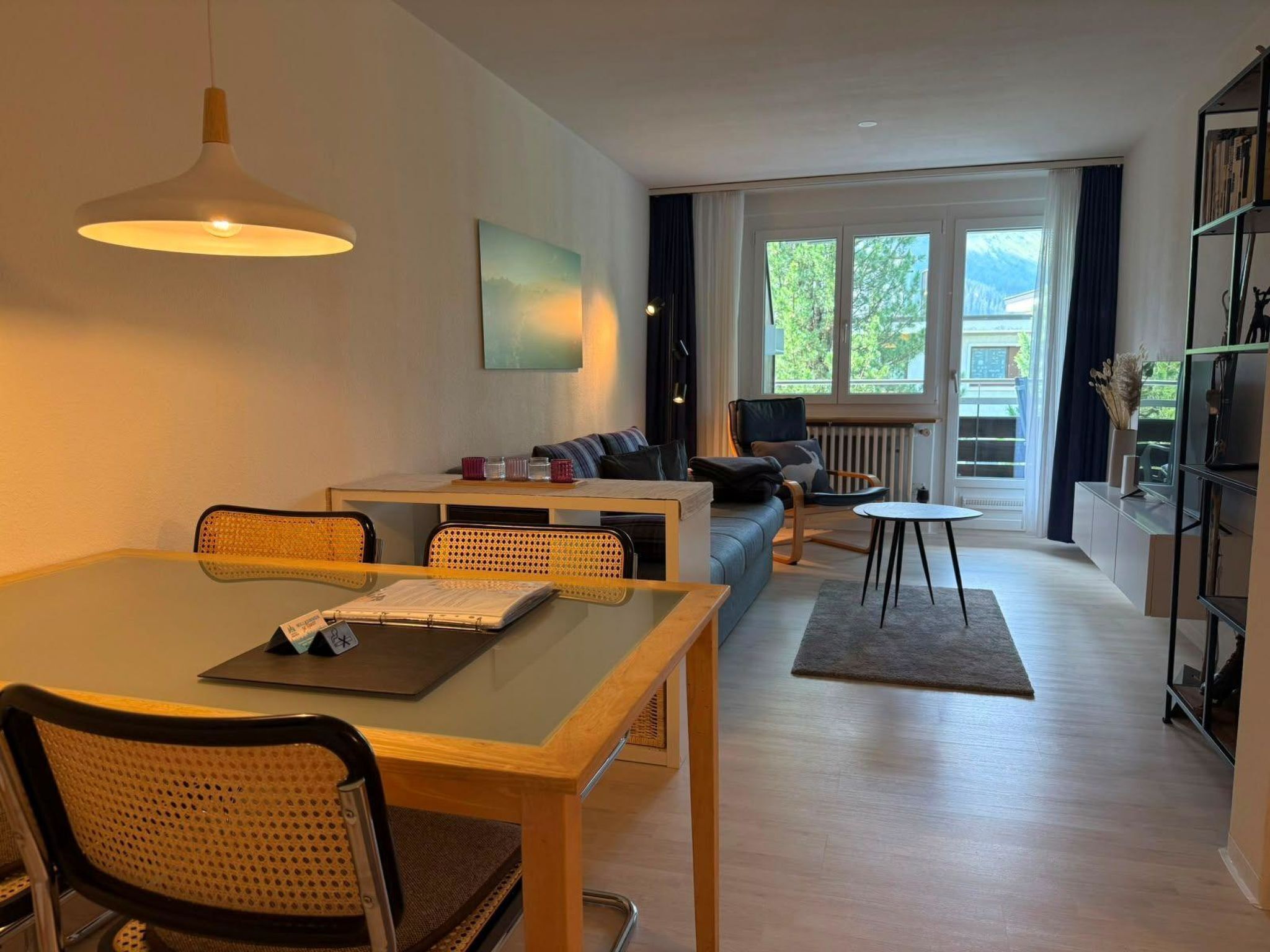 Una sala moderna con una mesa de comedor, sofá y vistas al exterior.