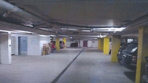 A parking garage with concrete floors, yellow pillars, and a few parked cars. - Derby 25 Appartement/Fewo, Dusche oder Bad, WC, 4-Bettwohnung by Interhome (Arosa)
