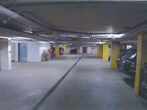 Eine Parkgarage mit Betonböden, gelben Säulen und einigen stehenden Autos.