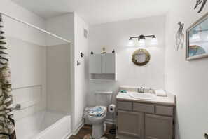 Et badeværelse med badekar, toilet, vask og underskab.