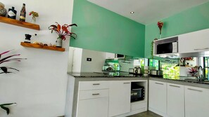 A modern kitchen with white cabinets, a microwave, a glass-top island, and various kitchen utensils. - 4 Bedroom Villa Sawadee 500 metres to beach SDV391 By Samui Dream Villas (Koh Samui)