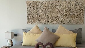 Camera d'albergo con un letto, cuscini, un elemento decorativo a parete e una composizione di asciugamani.