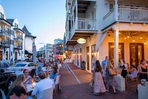 Eine belebte Straße mit Außenbereich eines Restaurants, Passanten und klassischer Architektur.