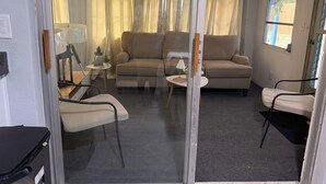 A room with a sofa, chairs, a small table, and a window.