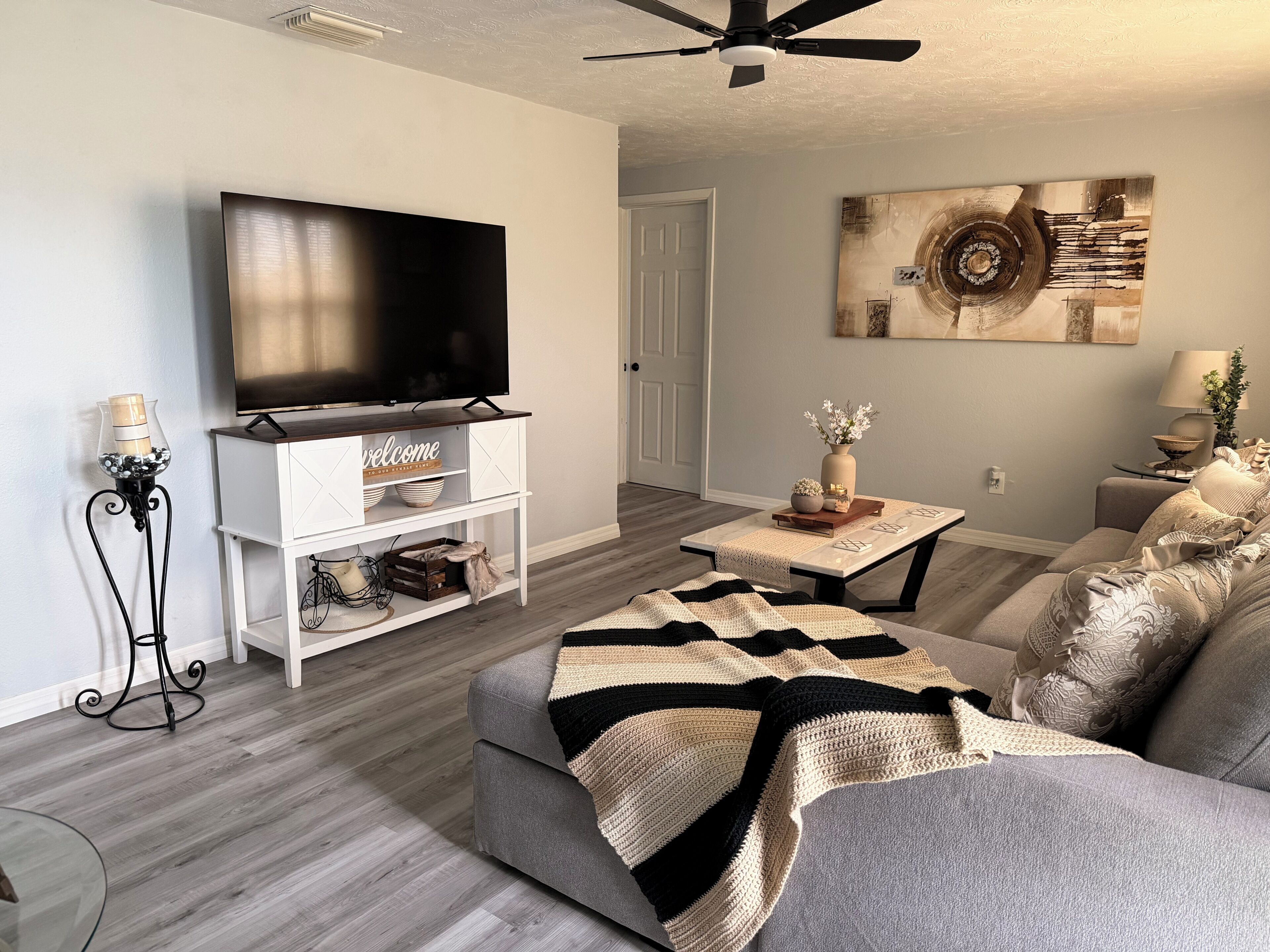 A living room with a flat-screen TV, a coffee table, a sofa, and a decorative wall piece.
