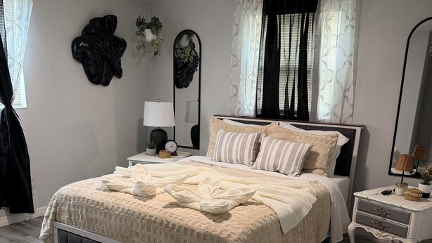 A bedroom with a bed, bedside tables, a ceiling fan, and a window with curtains.