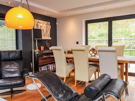 Una sala de estar moderna con sillones de cuero, una mesa de comedor y un ventanal grande.