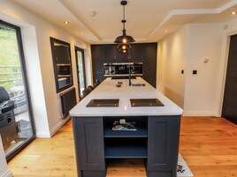 Cocina moderna con una isla central, muebles oscuros y vistas al exterior.