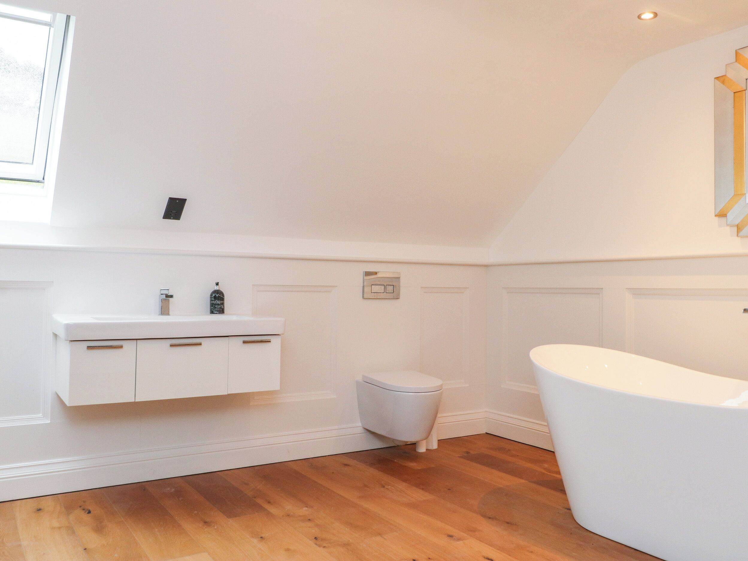 A bathroom with a white vanity, a toilet, and a freestanding bathtub.