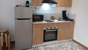 A compact kitchen with a refrigerator, microwave, stove, and wooden cabinets. - Le Bonaparte - Charming 2-room apartment near the port of Toulon (Toulon)