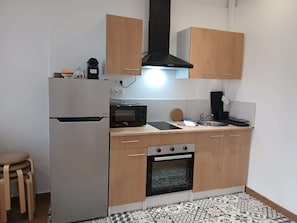 Eine kompakte Küche mit Kühlschrank, Mikrowelle, Herd und Holzschränken.