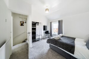 A bedroom with a bed, a desk, a chair, and a wardrobe.