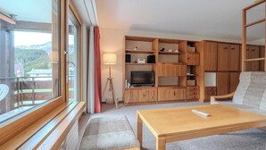 Quarto com sofá, mesa de madeira, TV e armários embutidos.