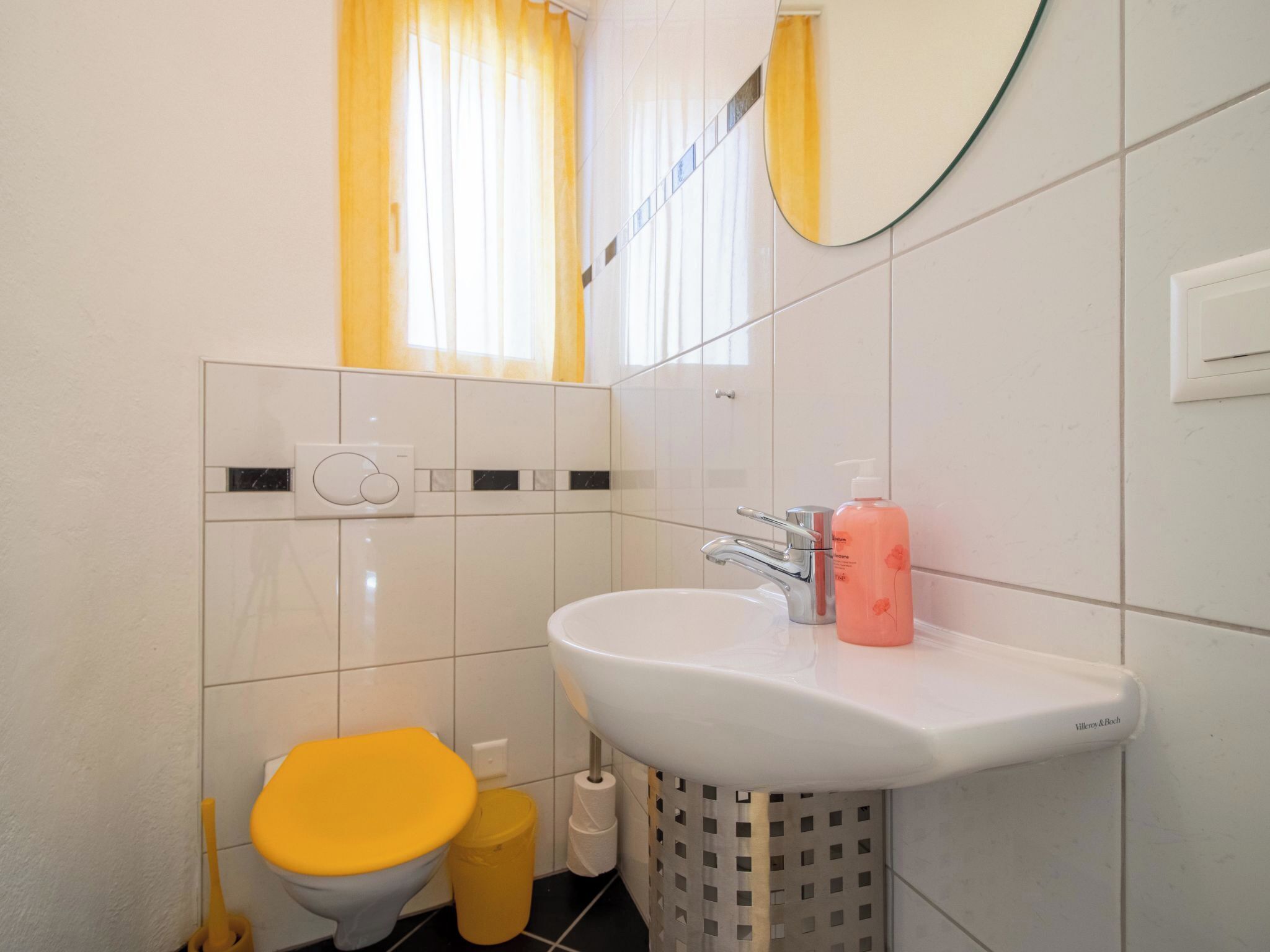 Un bagno con un lavandino bianco, un water giallo e uno specchio sopra il lavandino.