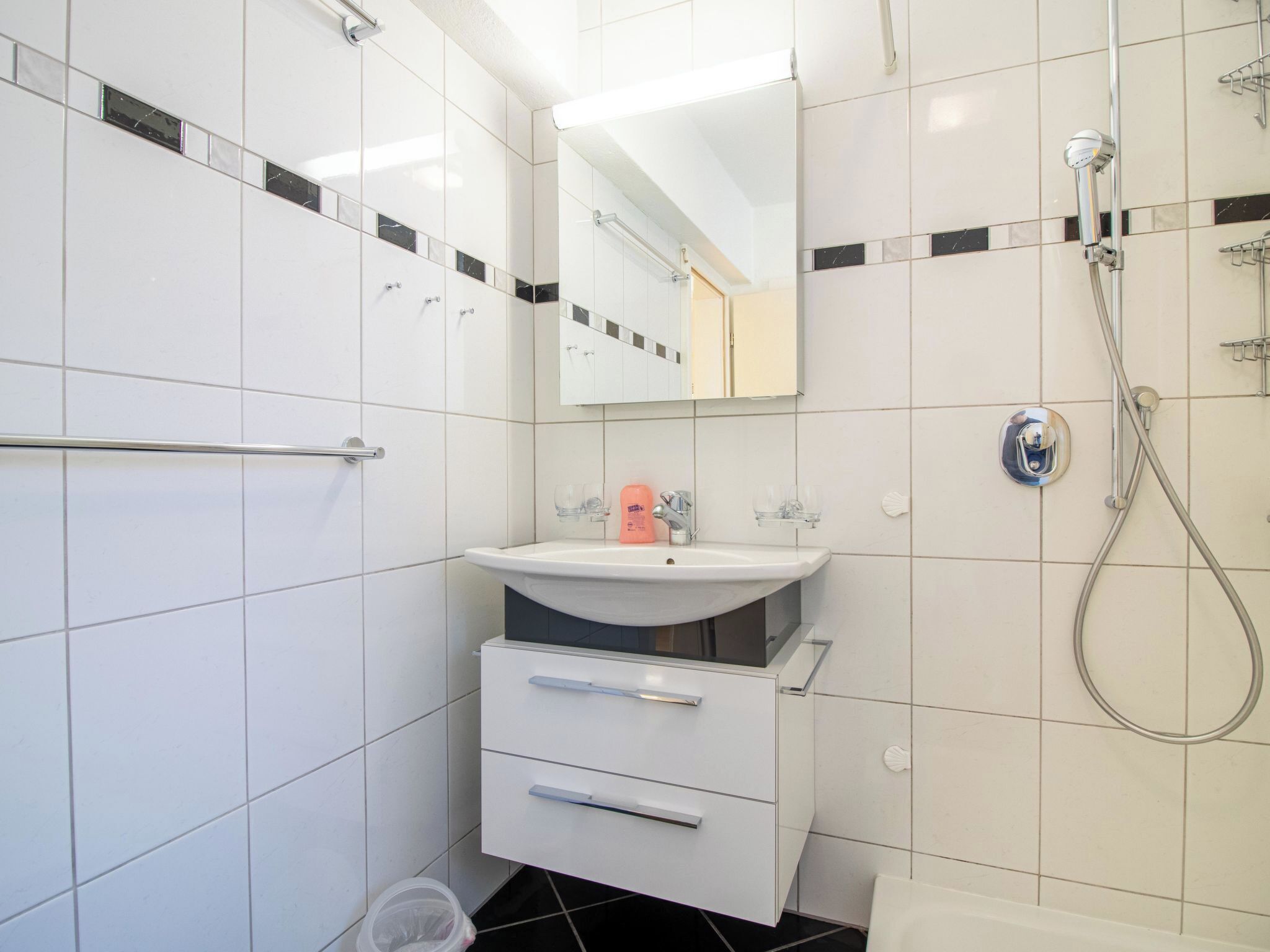 Ein modernes Badezimmer mit einem weißen Waschbecken, Spiegel und Dusche.