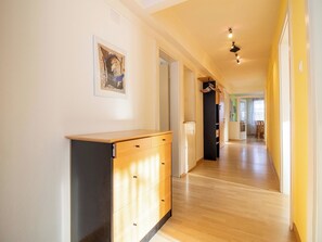 Un couloir doté d’un plancher en bois, d’une armoire noire et d’une porte donnant sur une autre pièce.