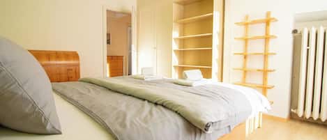 Un dormitorio con cama, cómoda de madera, armario y radiador.