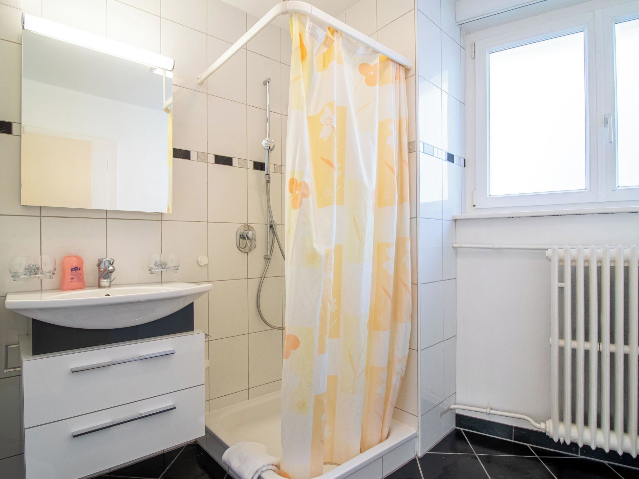 A bathroom with a shower, sink, and mirror.