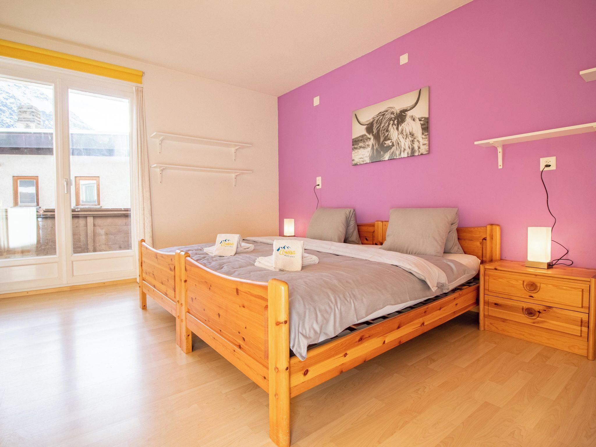 A bedroom with a wooden bed, a purple wall, and a window with curtains.