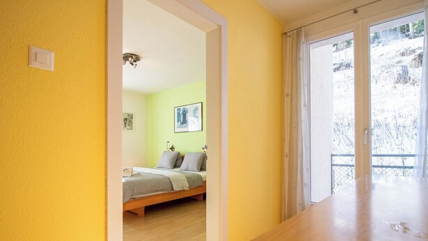 Una habitación con cama, una mesa de madera y vistas a un paisaje nevado a través de una ventana.