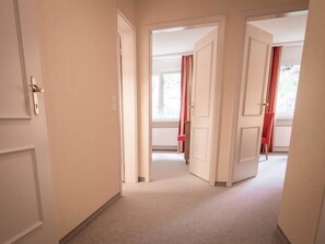 A corridor with white doors leading to rooms, carpeted floor, and a window with red curtains. - Chalchboda 1 Appartement/Fewo,  , 6-Bettwohnung by Interhome (Arosa)