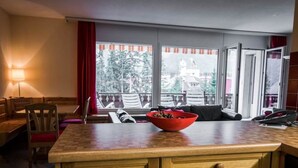 Habitación de hotel con un mostrador de madera, un frutero, un sofá y vistas al exterior.