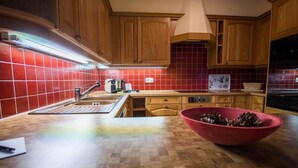 Una cocina con armarios de madera, salpicadero de baldosas rojas, encimera de madera, un lavamanos y un tazón rojo sobre la encimera.