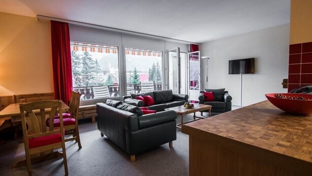 Una sala de estar moderna con un sofá, una mesa de comedor y un ventanal grande.