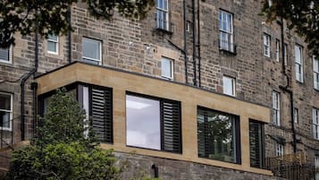 A modern building with stone facade, large windows, and a flat roof.
