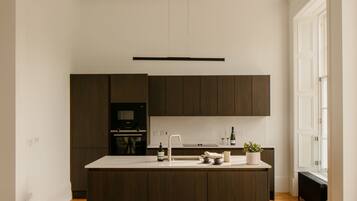A modern kitchen with dark wood cabinets, a central island, and a built-in oven.