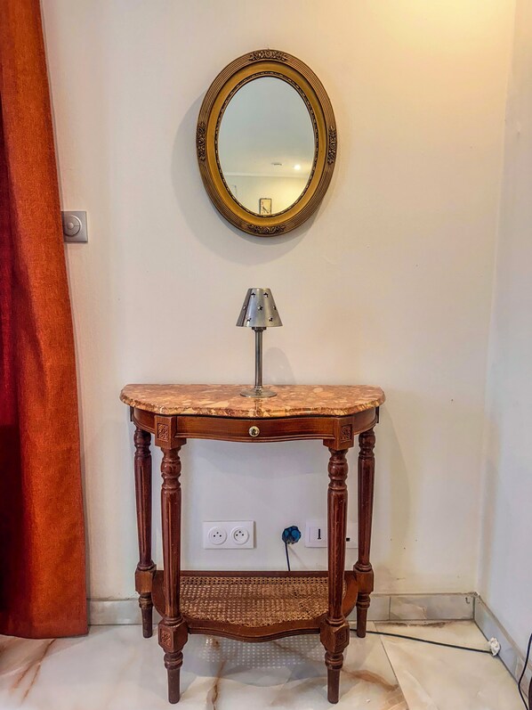 Ein Holzkonsolentisch mit einem Spiegel darüber, eine Lampe auf dem Tisch und eine Steckdose darunter.