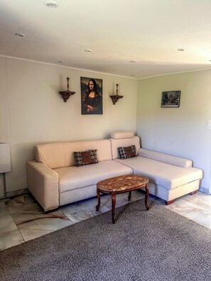 Ein Wohnzimmer mit einem beigefarbenen Sofa, einem Couchtisch, Wandbildern und Einbauleuchten.