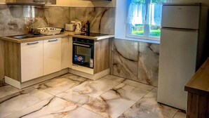 Una cucina moderna con pavimento in marmo, elettrodomestici integrati e una finestra che illumina con luce naturale.