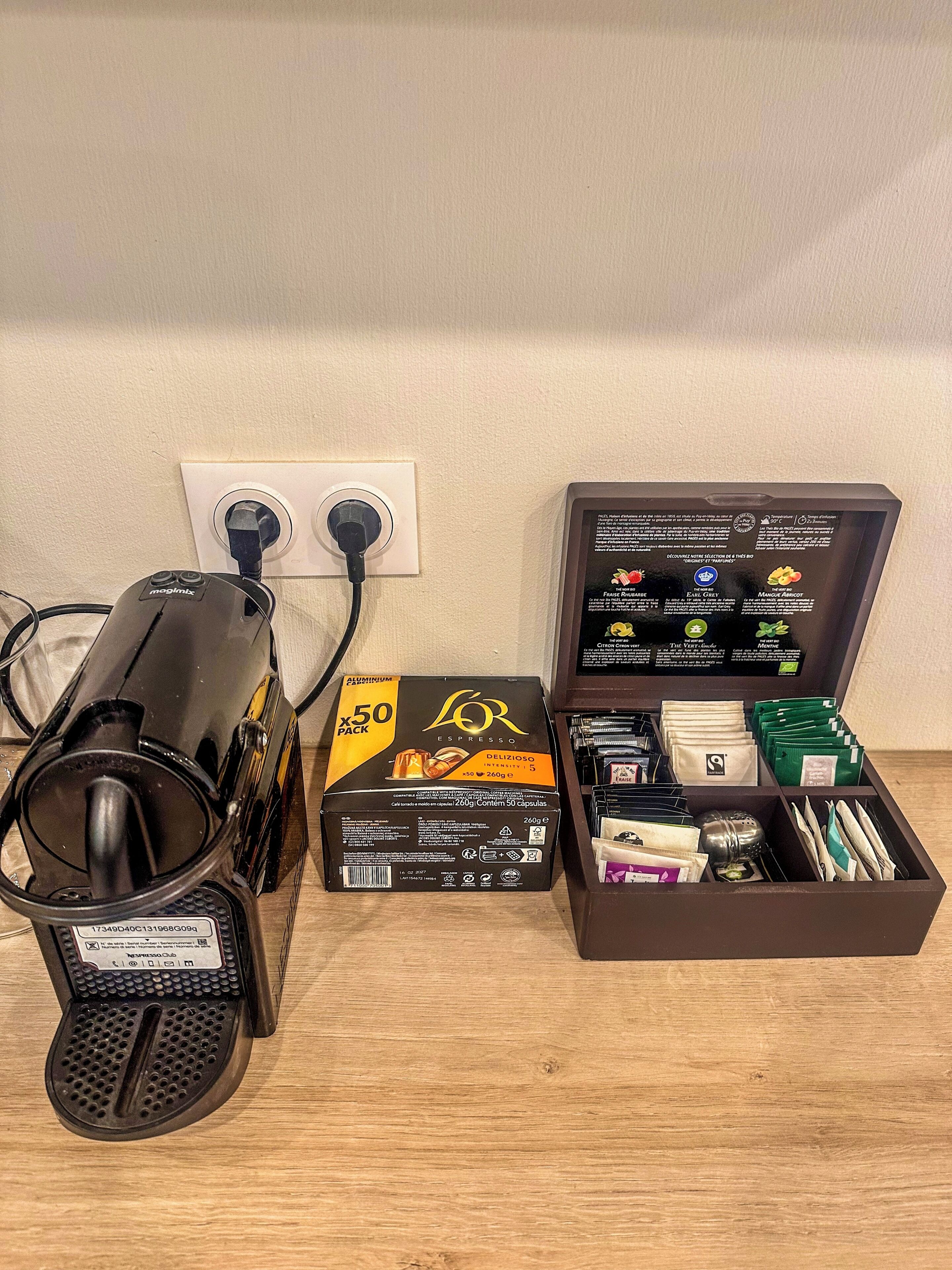 A coffee machine, a box of coffee capsules, and a storage box with coffee capsules and sachets.